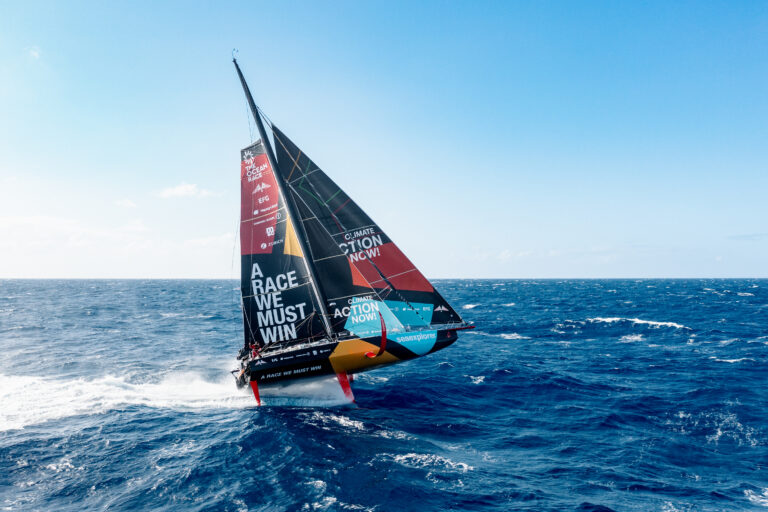 Malizia IMOCA boat foiling at high speed over the open ocean.